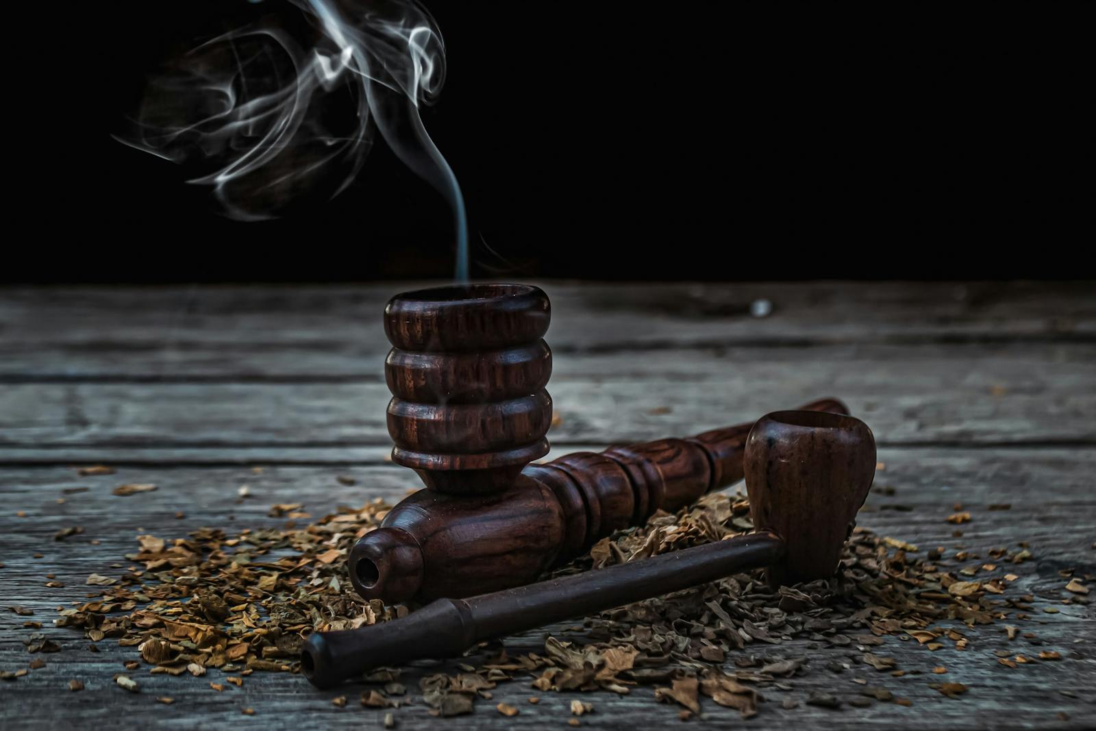 Traditional pipes displayed with smoke on a dark table